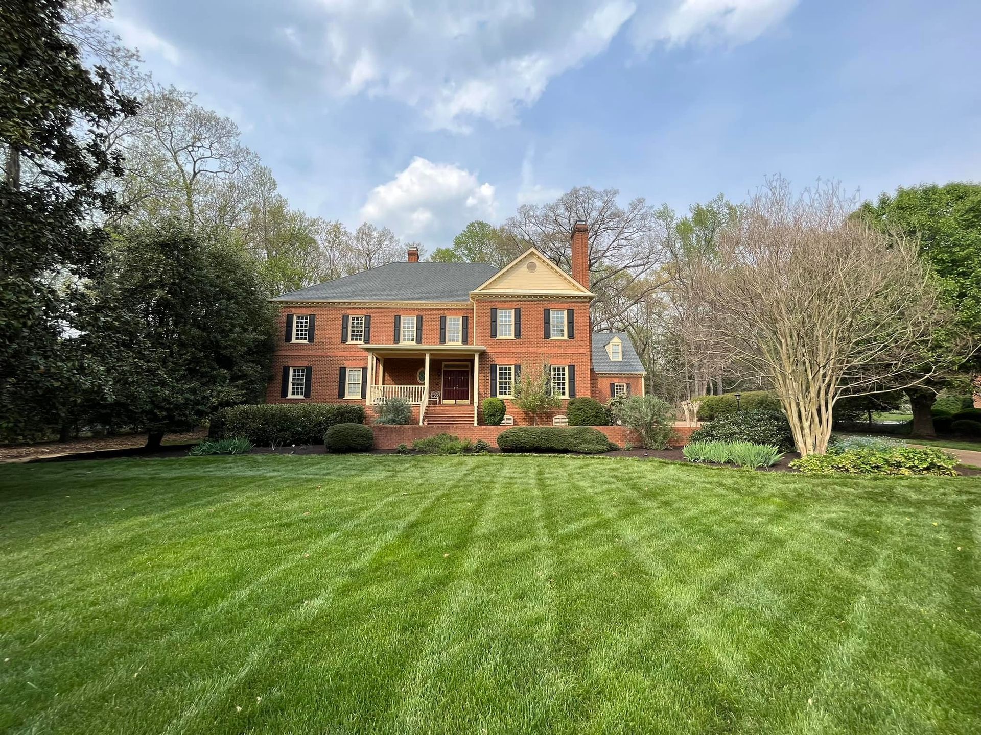 A large brick house with a large lawn in front of it.