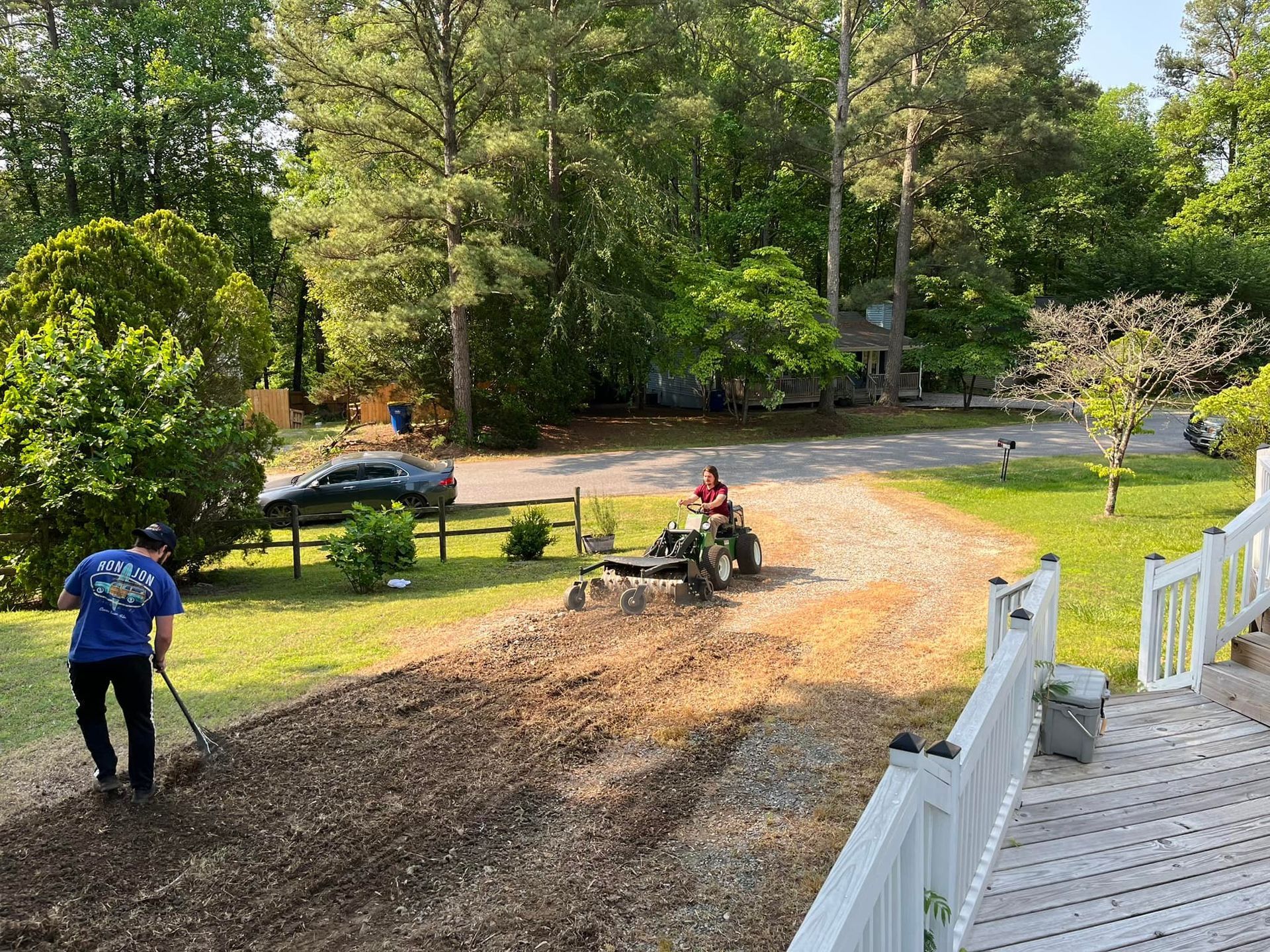 A man is raking the ground in front of a tractor.
