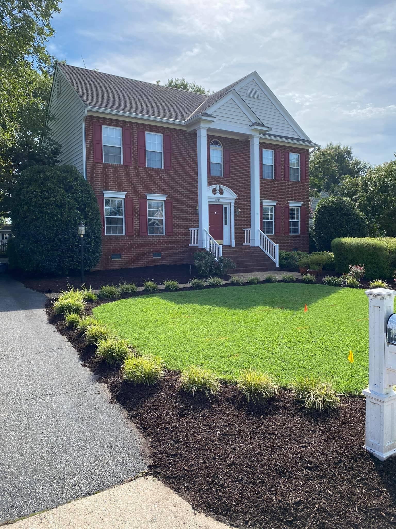 A large red brick house with a large lawn in front of it
