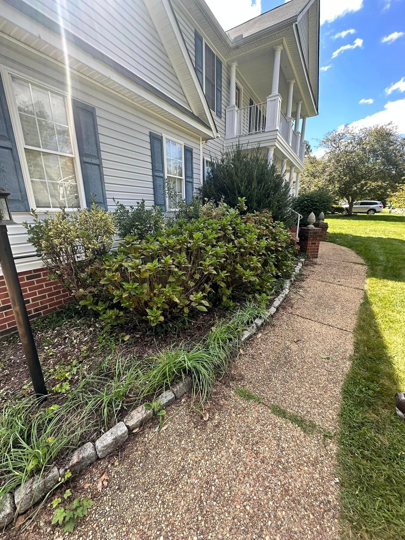 A sidewalk leading to a large white house with a porch.