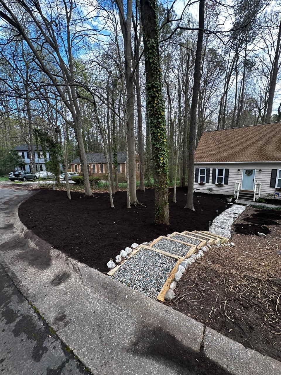 A house with a walkway leading to it is surrounded by trees.