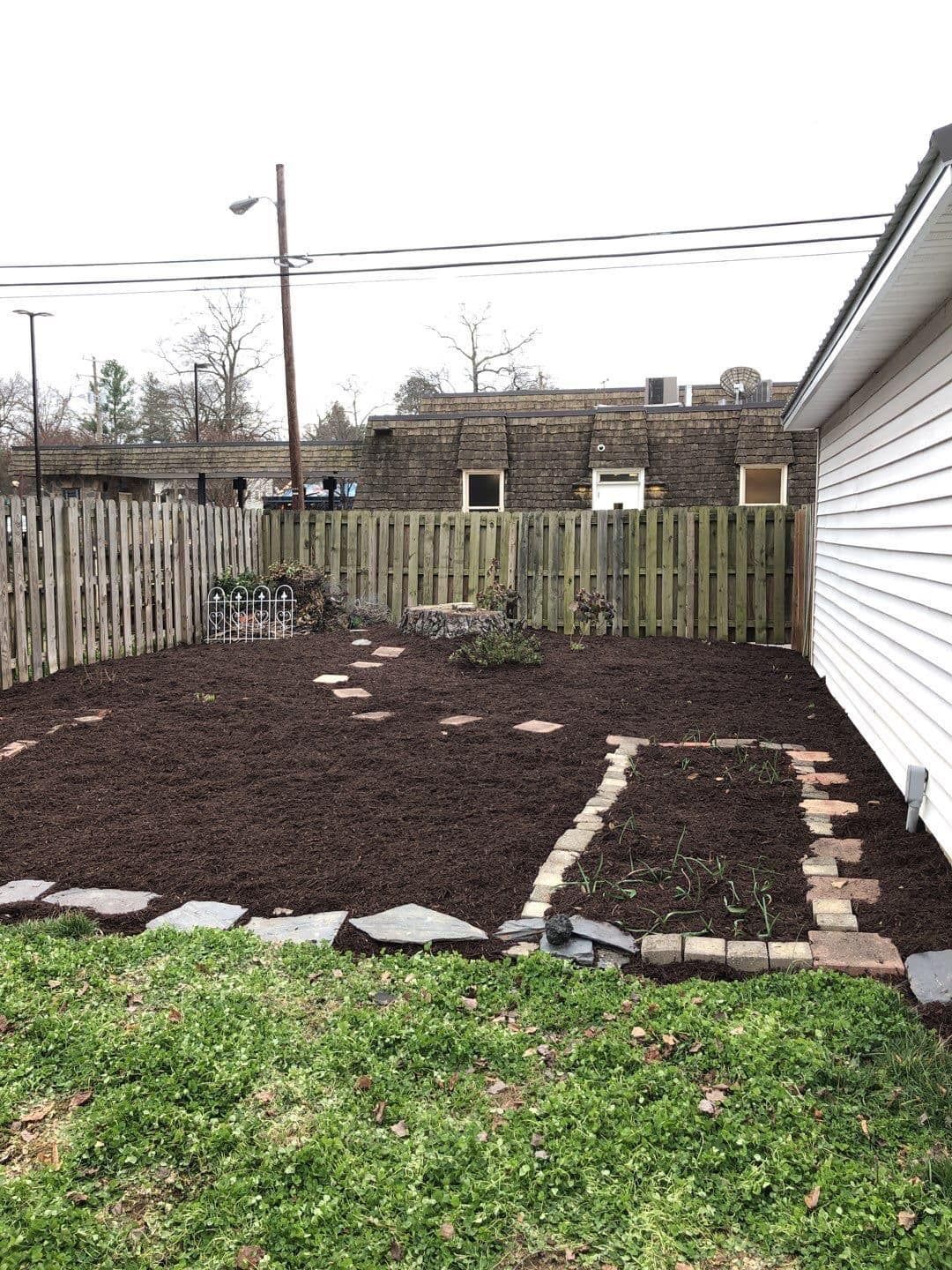 A backyard with a fence and a garden in the middle of it.