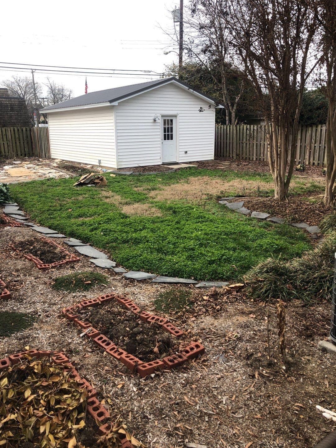 A backyard with a shed and a lot of grass and bricks.