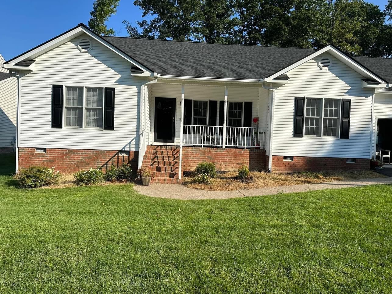 A white house with a black roof and a porch