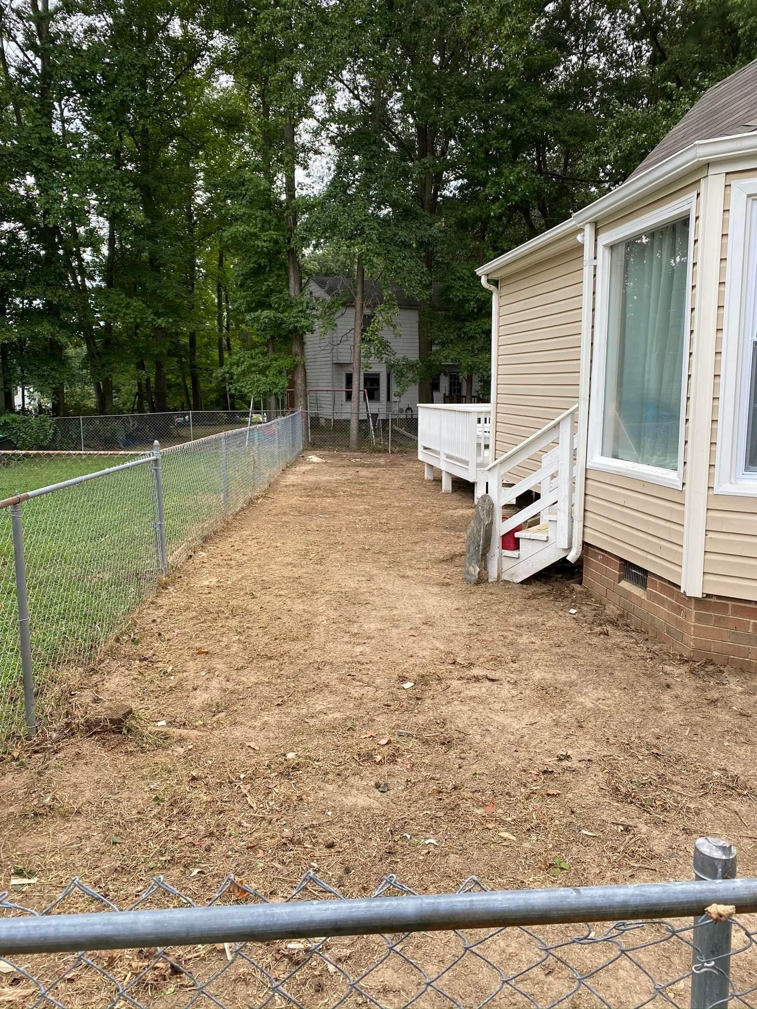 A chain link fence surrounds a dirt yard in front of a house.