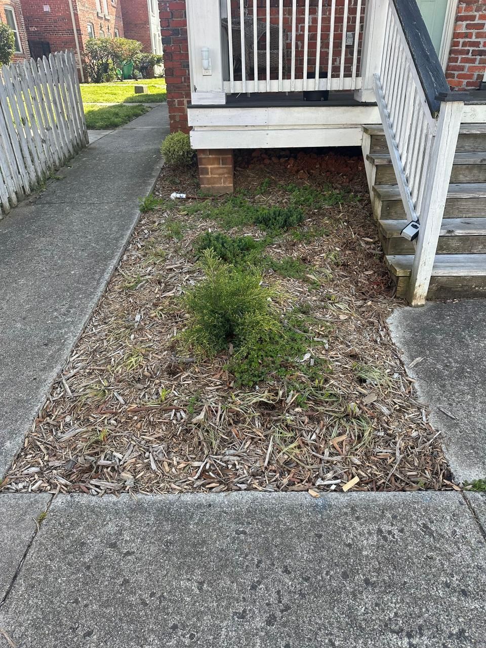 A brick house with stairs and a sidewalk in front of it.