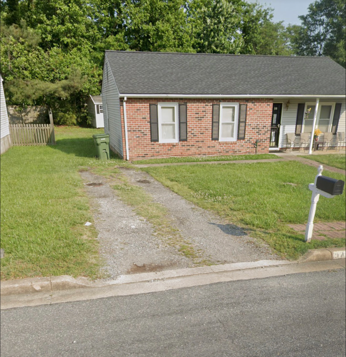 A brick house with a black roof and white shutters