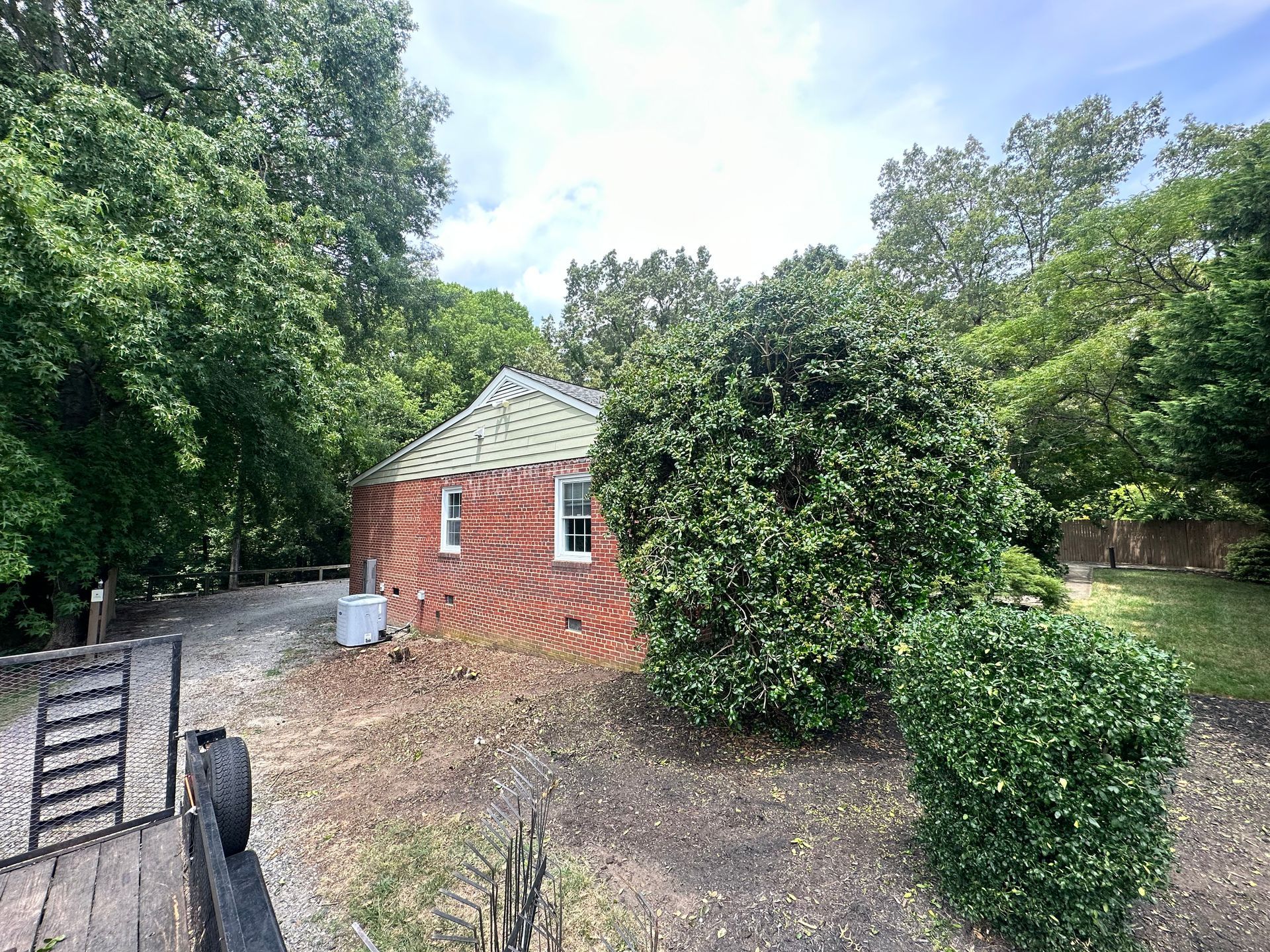 A small brick house is surrounded by trees and bushes.