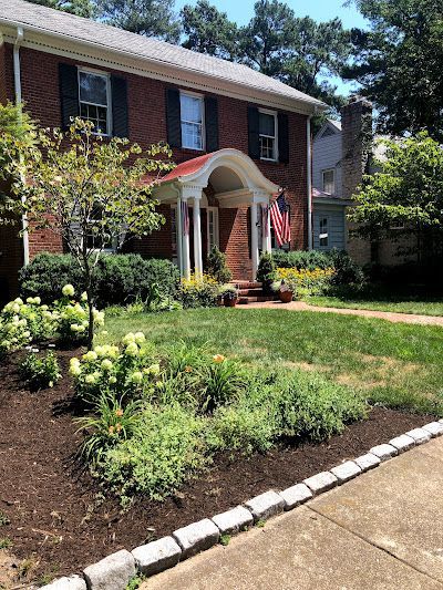 A brick house with a large lawn and a flag in front of it.