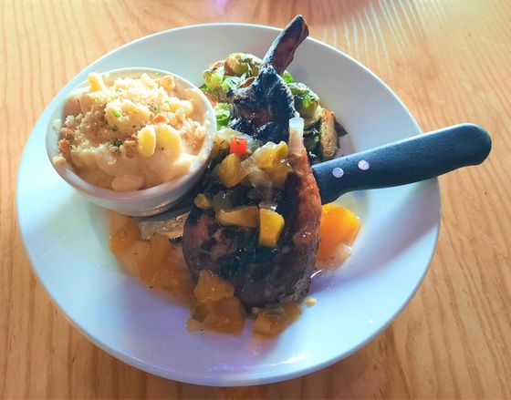 Plate of food: pork chop with mango salsa, mac and cheese, brussels sprouts.