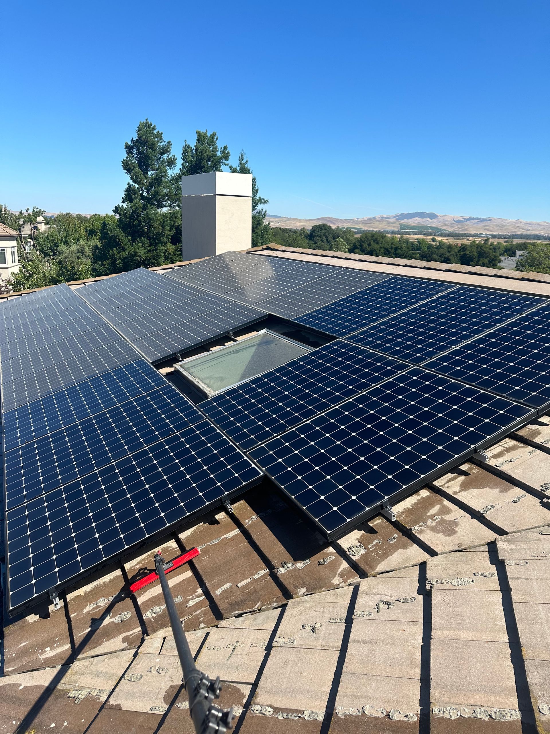 A man is cleaning a solar panel with a mop.