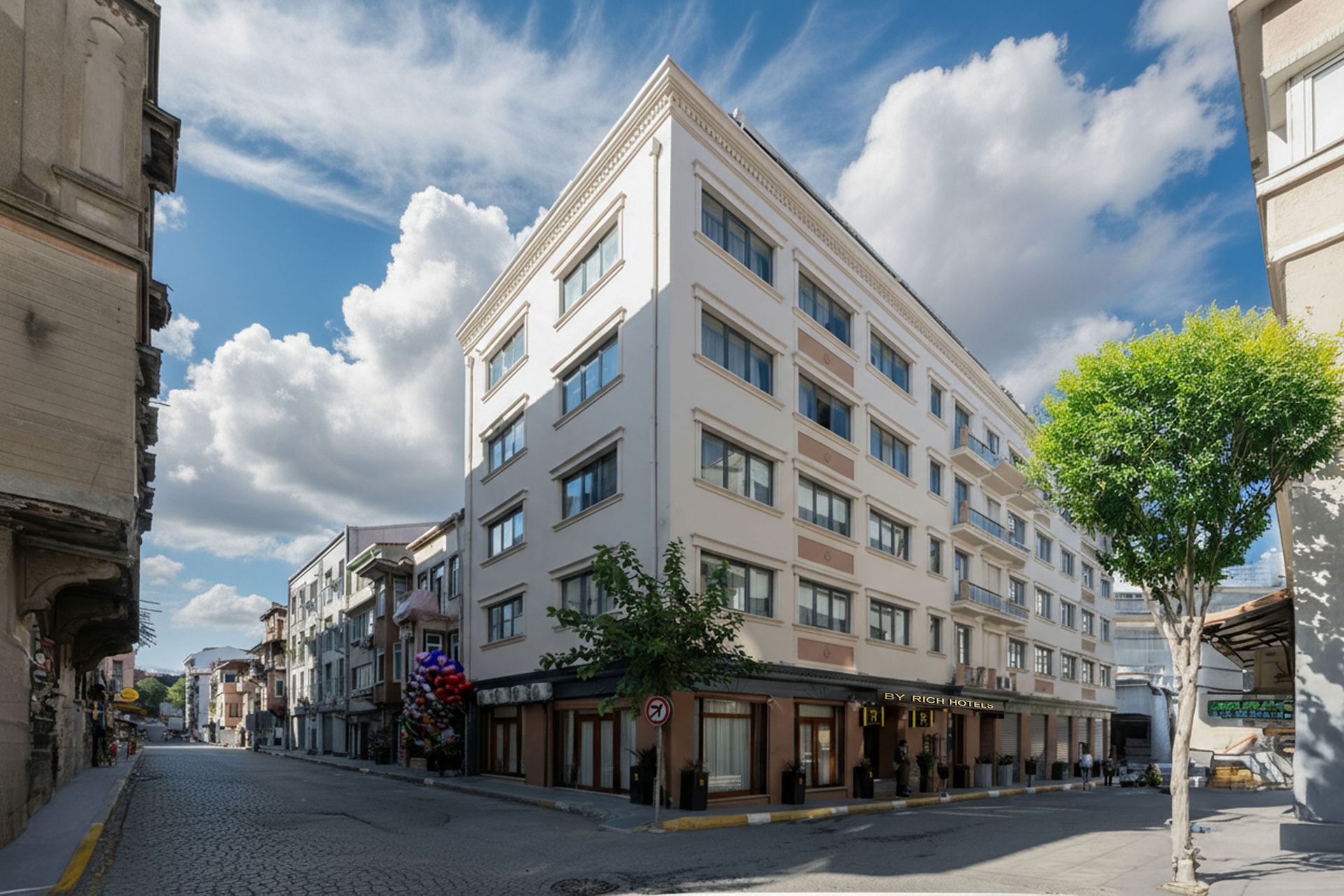 Mays Otel | A multi-story hotel building with a white and beige exterior, located on a street corner.