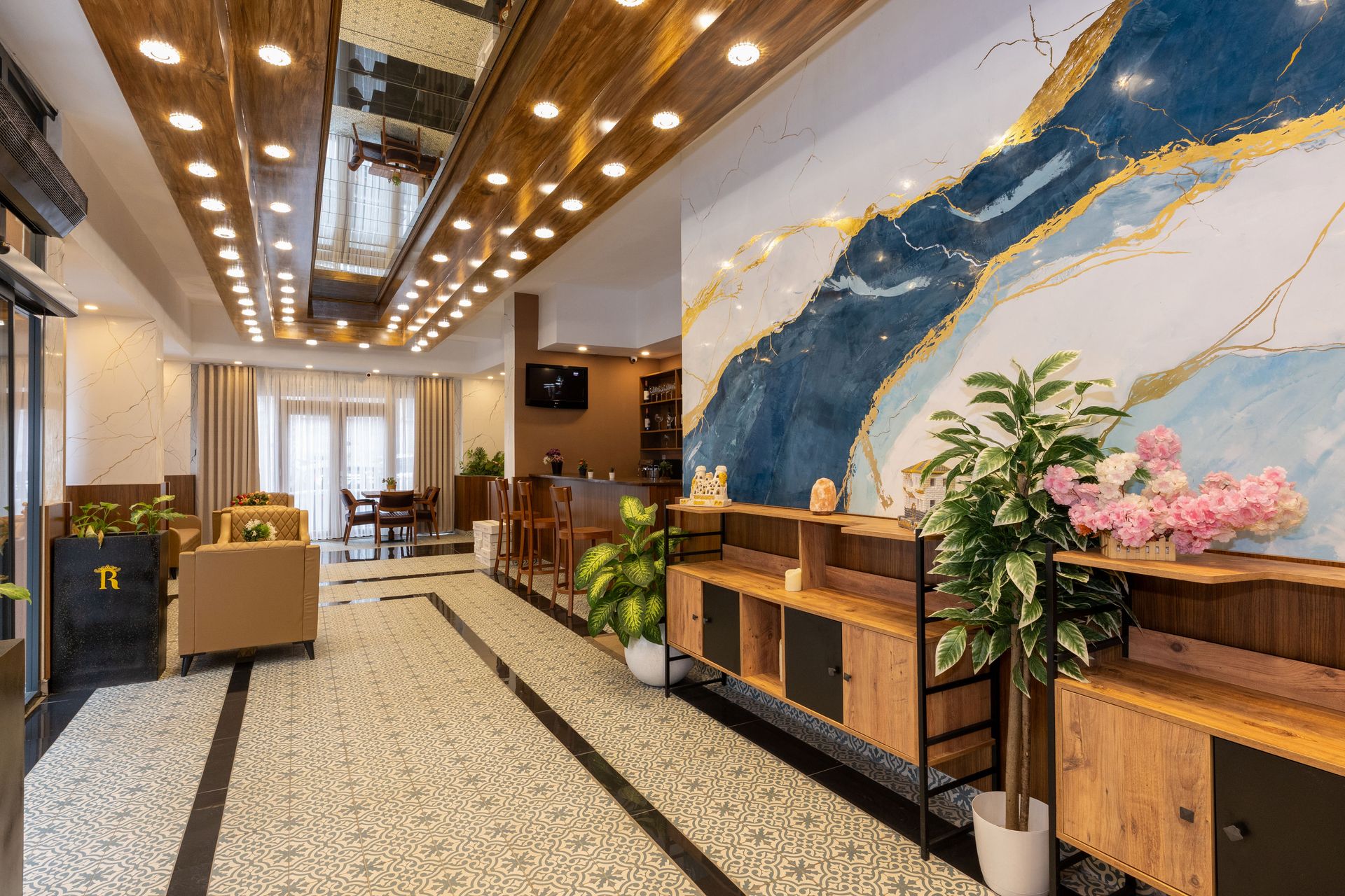 Mays Otel | Lobi | Hotel lobby with wood accents, large art wall, and potted plants.