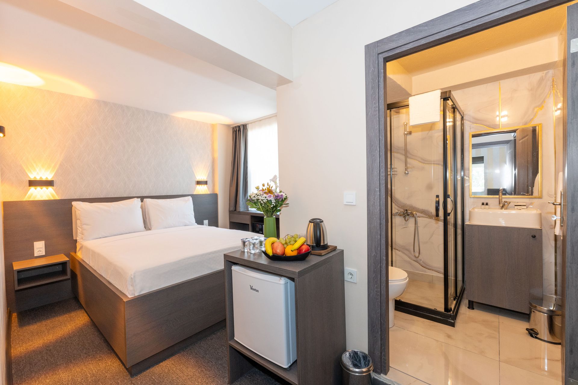 Mays Otel | Hotel room with bathroom visible through the open door, small refrigerator and double bed.