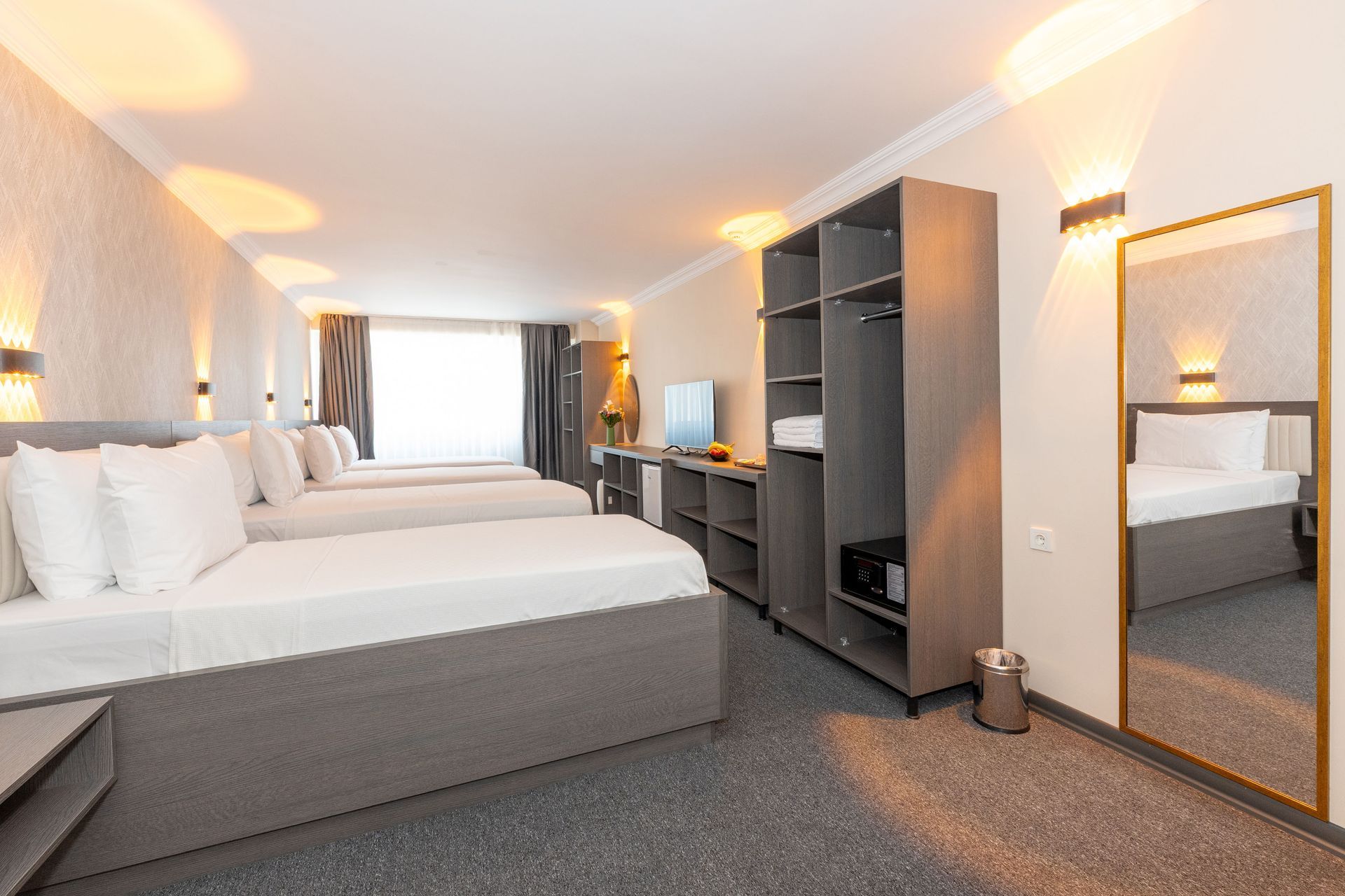 Mays Otel | Three-bedroom hotel room, grey carpet, wardrobe, mirror. Decorated brightly with neutral colors.