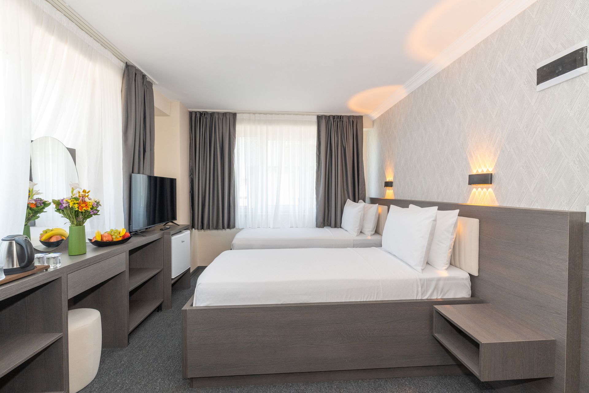 Mays Otel |Twin Room | Hotel room with two twin beds, desk, TV, and gray decor.