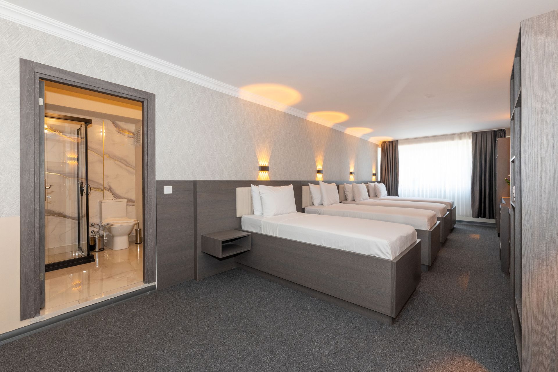 Mays Otel | Hotel room with three single beds, a bathroom visible, and neutral-colored walls.