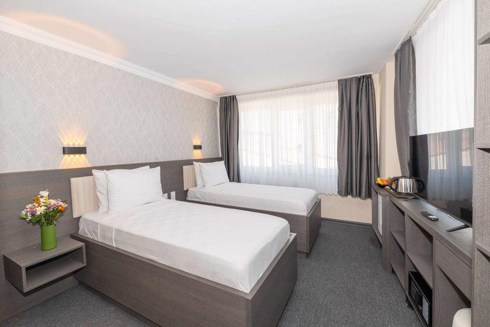 Mays Otel | A hotel room with two beds, a window with curtains, and a television.