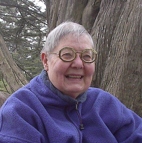Smiling person in a purple fleece jacket outdoors among trees