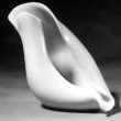 White sculptural chair with a curved, abstract shell design on a dark background
