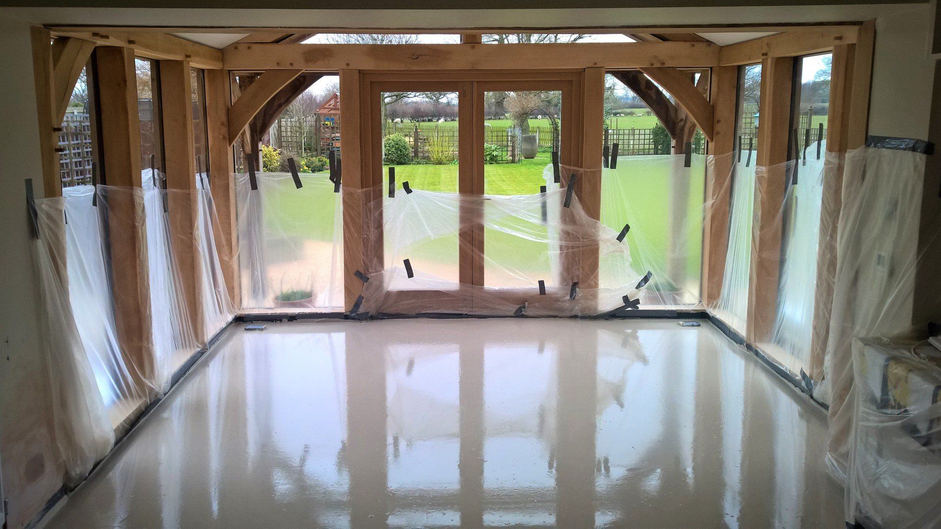 Empty room with polished white floor and large windows overlooking a green lawn