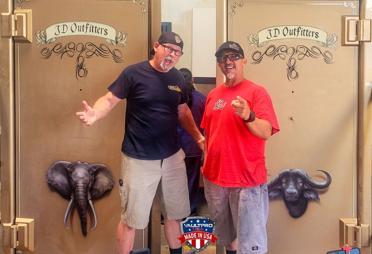 Two men posing in front of decorated doors, one in a navy shirt and one in a red shirt.