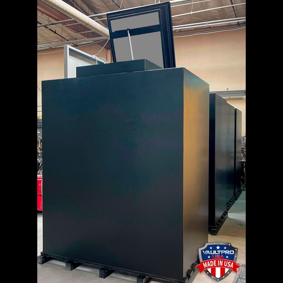 Large black server cabinet in an industrial room with a red-and-white badge near the bottom right.