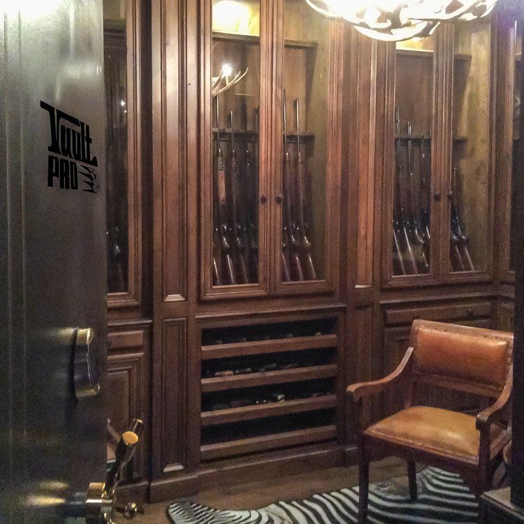 Wood-paneled wine cellar with glass cabinet doors, wine racks, and a leather chair