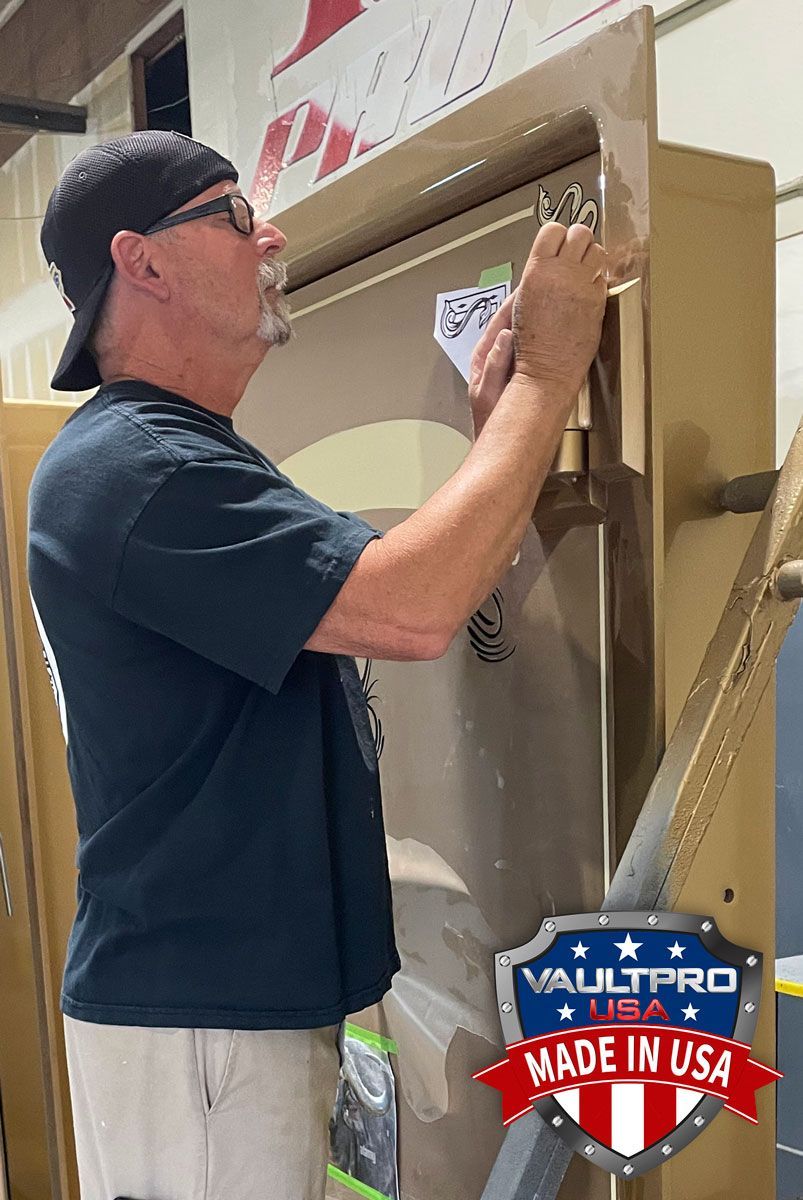 Worker in black shirt installs signage on a cardboard display in a warehouse aisle.