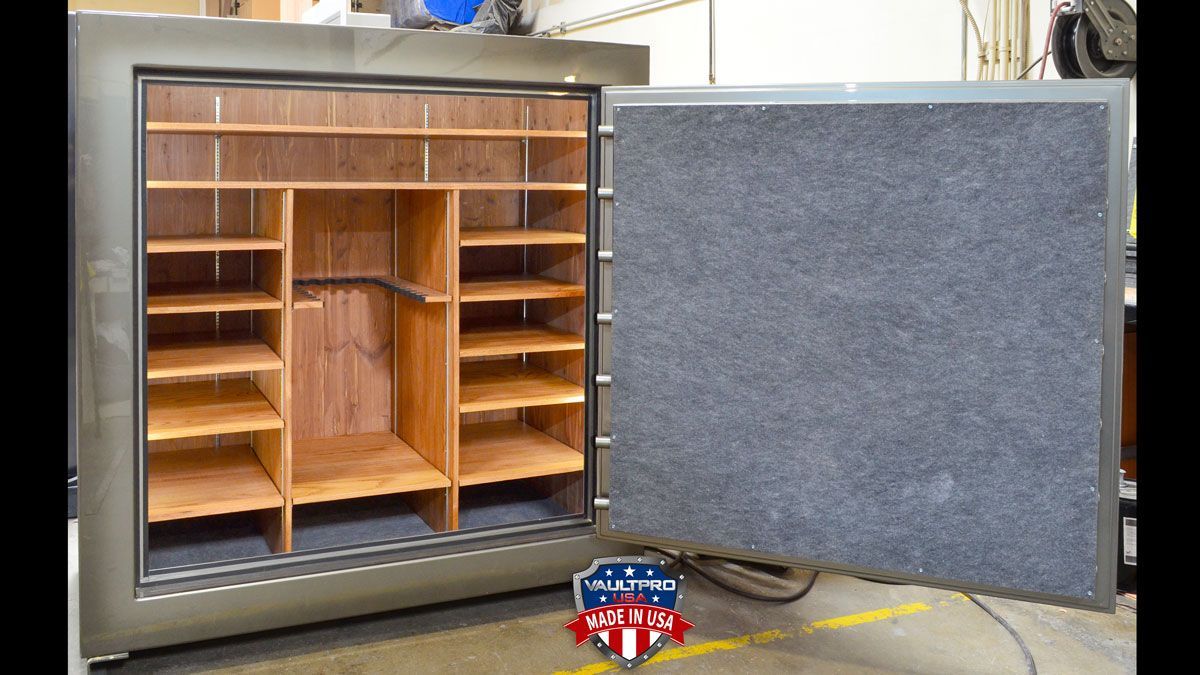 Open safe with gray door swung open, showing wooden shelves and compartments inside.
