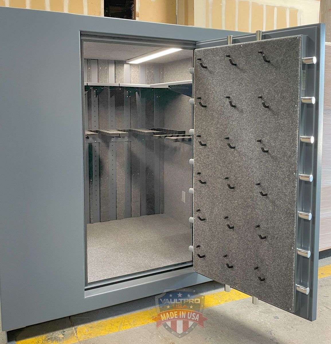 Open gray steel vault door with thick insulation, revealing an empty secure room inside.