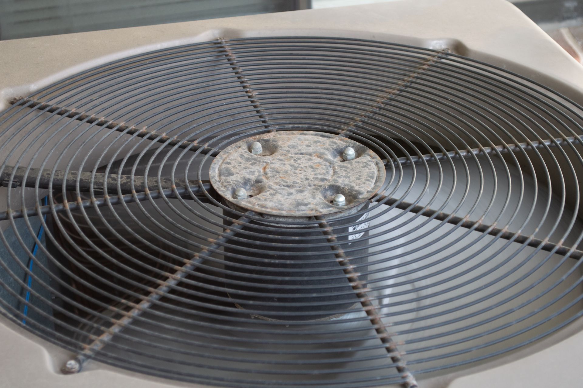Close-up of a dusty outdoor air conditioner fan grille and blades