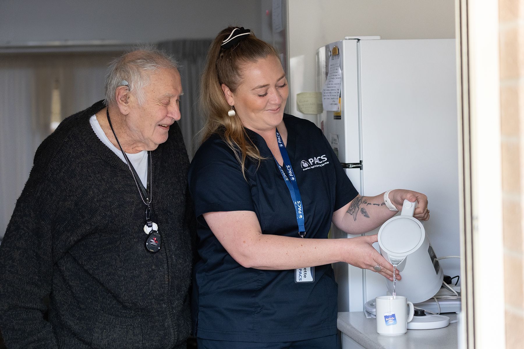 Caregiver Pouring Hot Water Into a Mug for a Person in a Kitchen — Premium Aged & Community Services In Moree, NSW