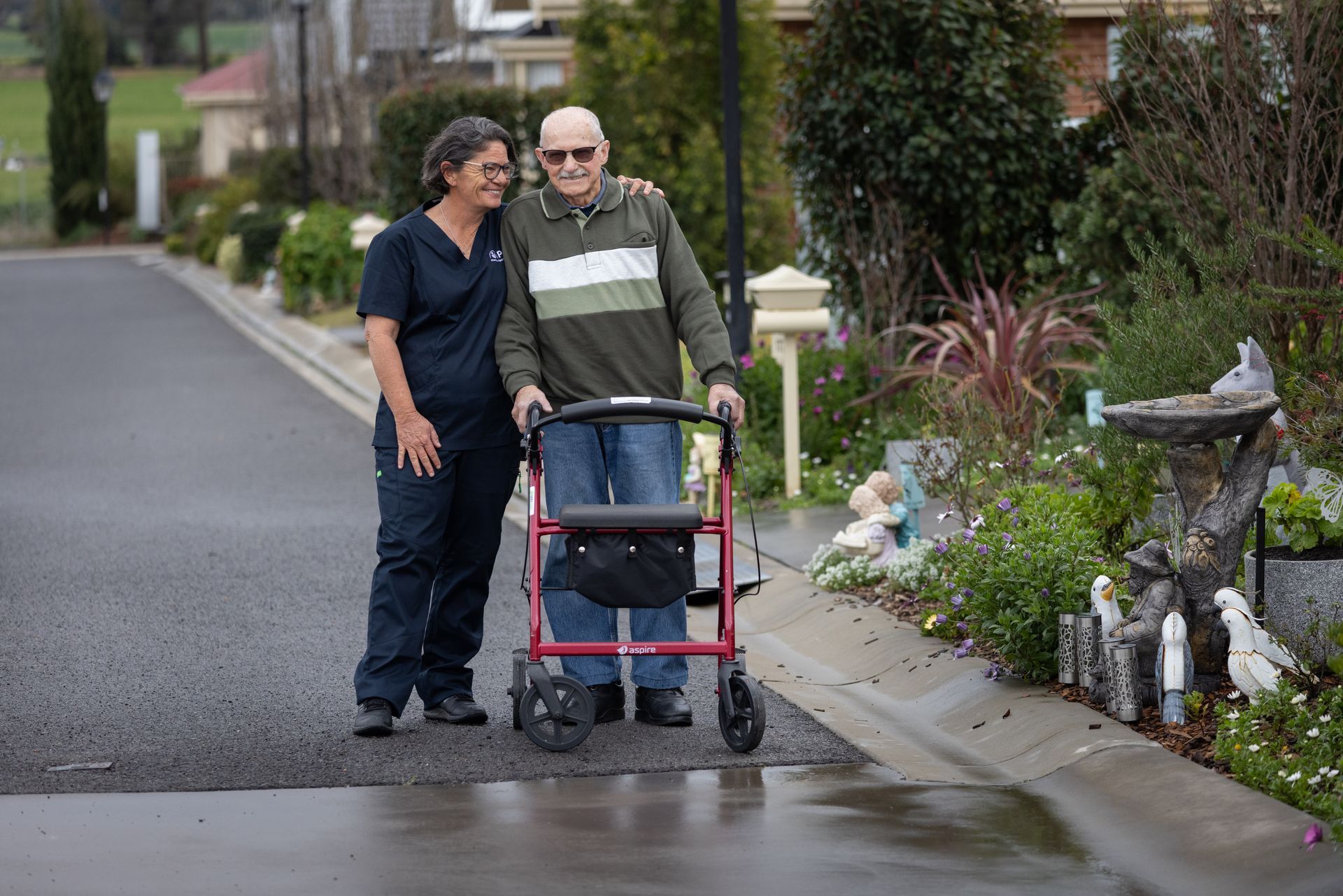 Person in a Blue Uniform Washes a Dish in a Sink, Smiling — Premium Aged & Community Services In Tamworth, NSW