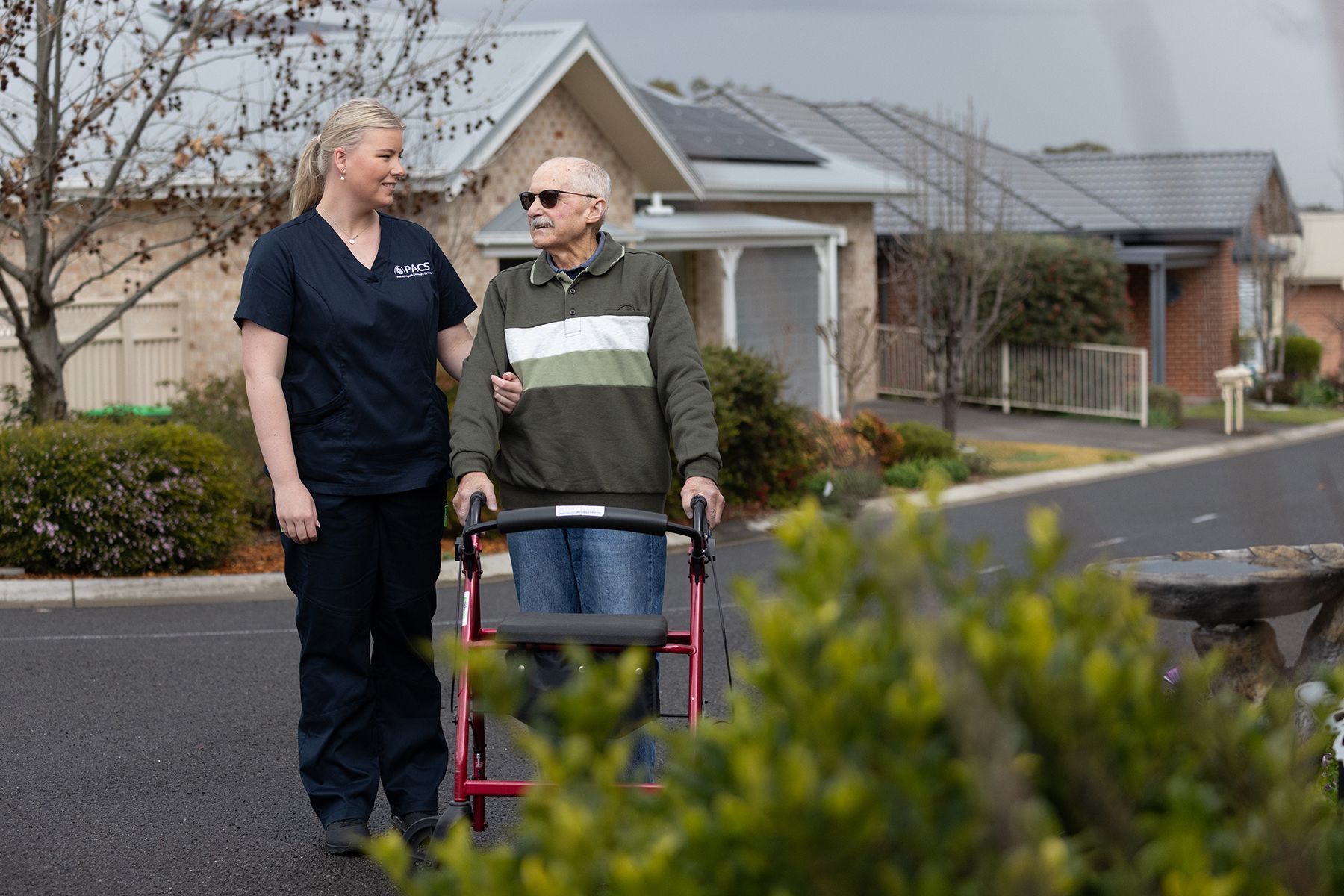 Caregiver Assists a Person Using a Walker Down a Residential Street — Premium Aged & Community Services In Tamworth, NSW