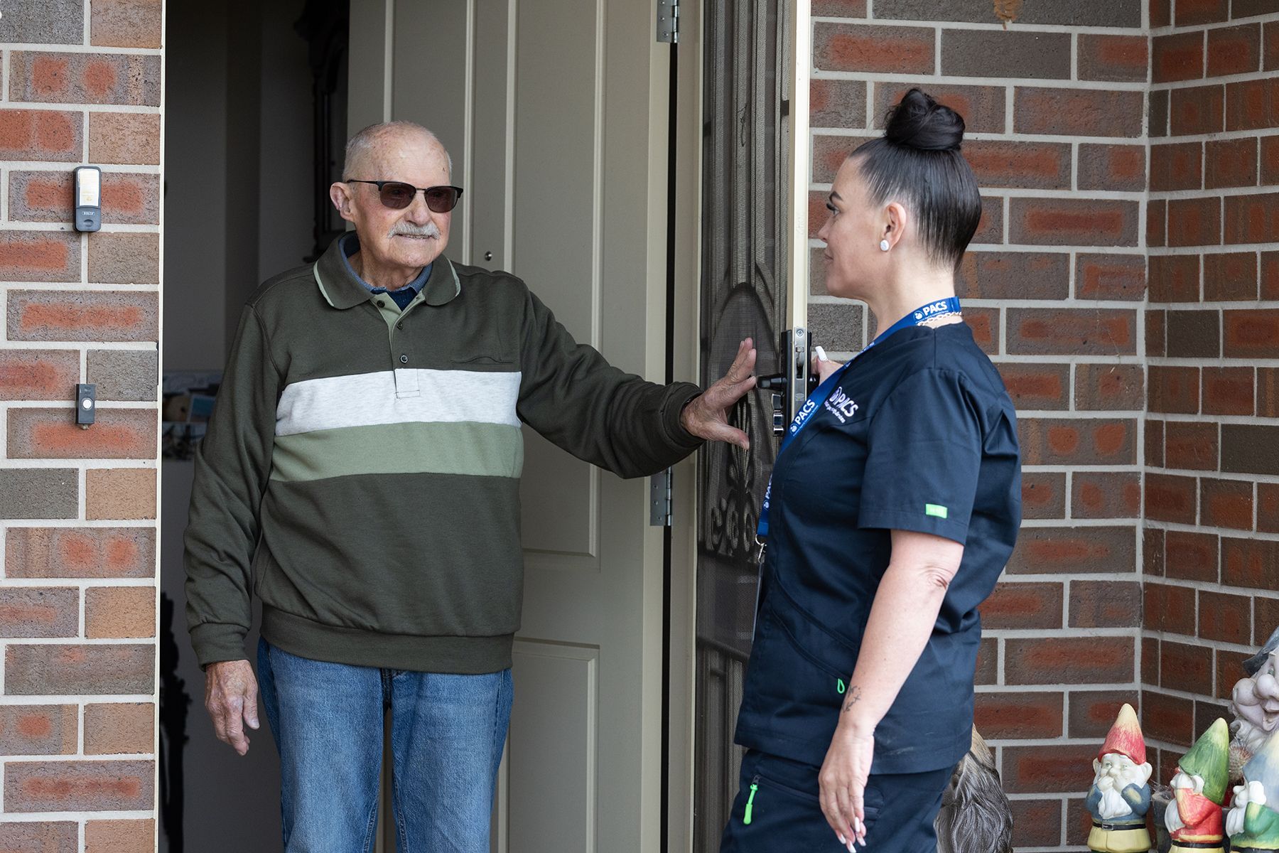 Man in Sunglasses Talking to Woman at Doorway; Brick Exterior — Premium Aged & Community Services In Tamworth, NSW