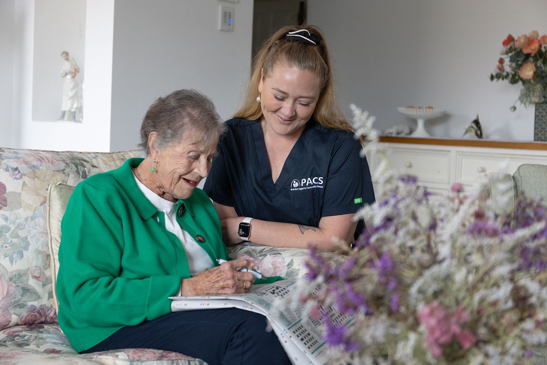 Person in a Blue Uniform Washes a Dish in a Sink, Smiling — Premium Aged & Community Services In Tamworth, NSW