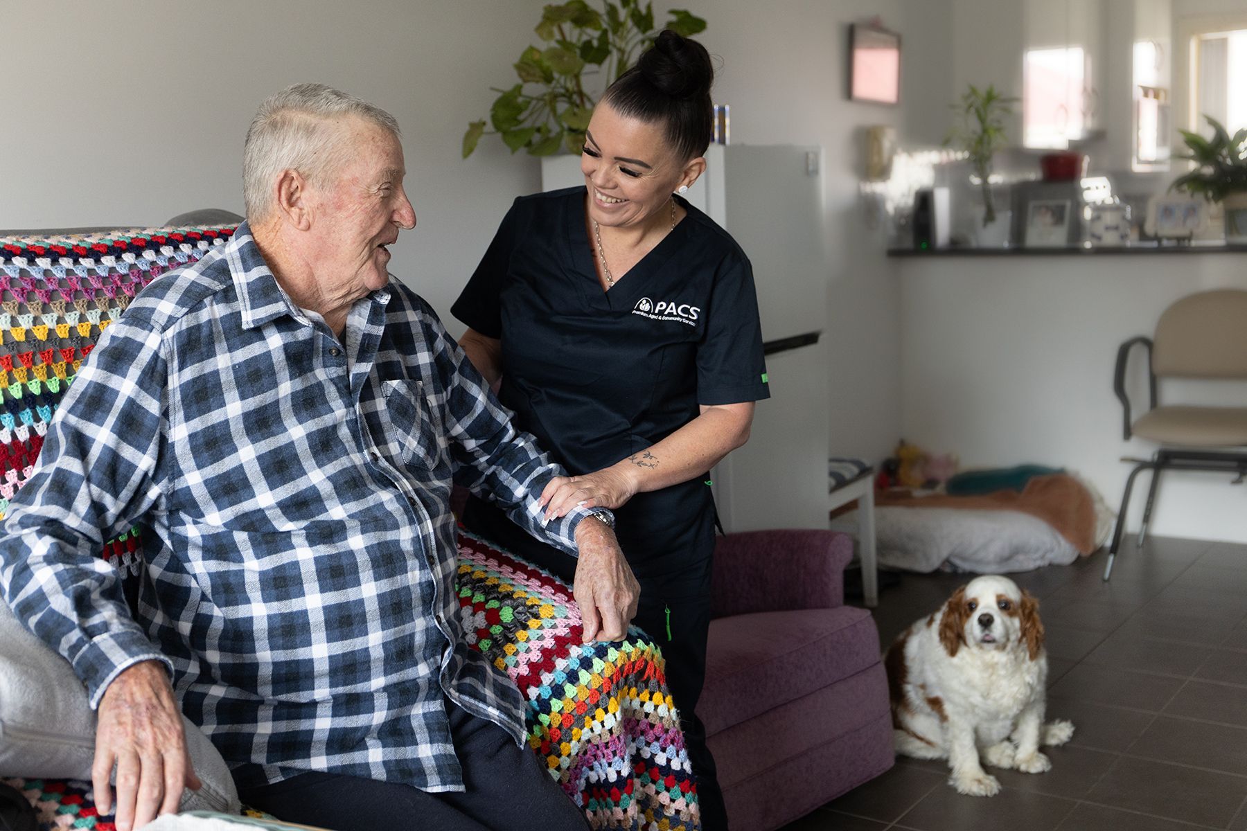 Caregiver Assisting an Older Person in a Home Setting; Dog Present — Premium Aged & Community Services In Woy Woy, NSW