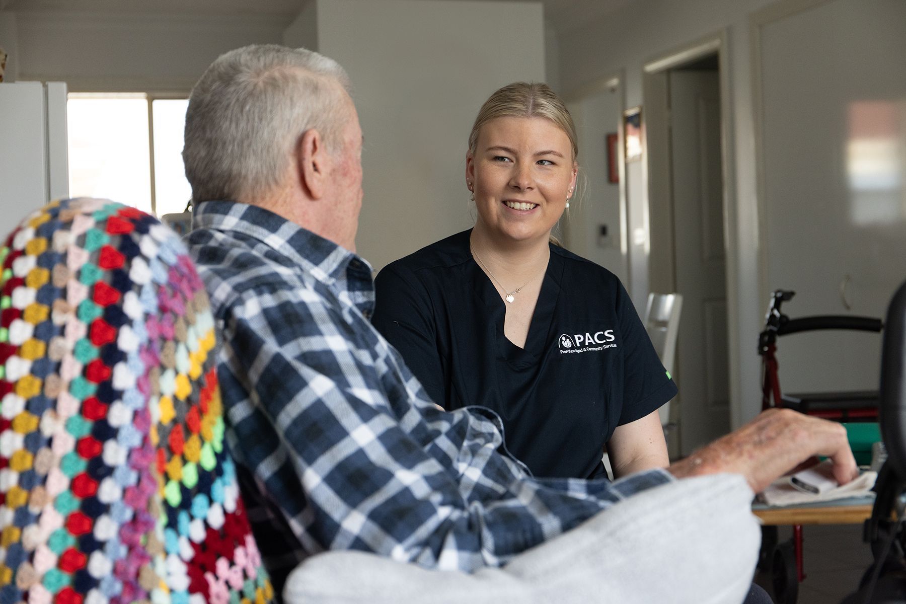 Caregiver Smiles at Elderly Man; They Sit Indoors — Premium Aged & Community Services In Toowoomba, QLD