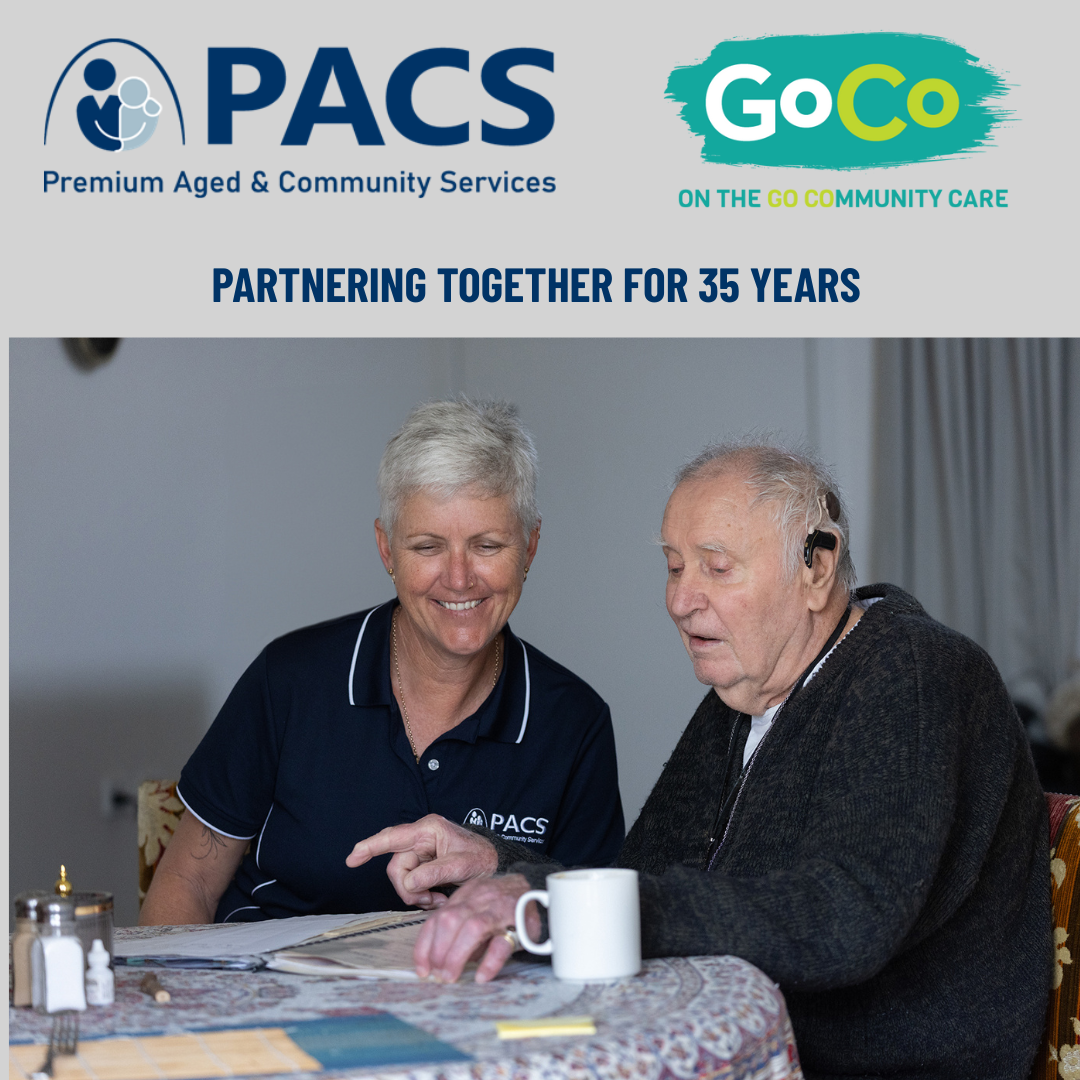 A Caregiver and Older Man Sit at a Table Looking at a Photo Album — Premium Aged & Community Services In Tamworth, NSW
