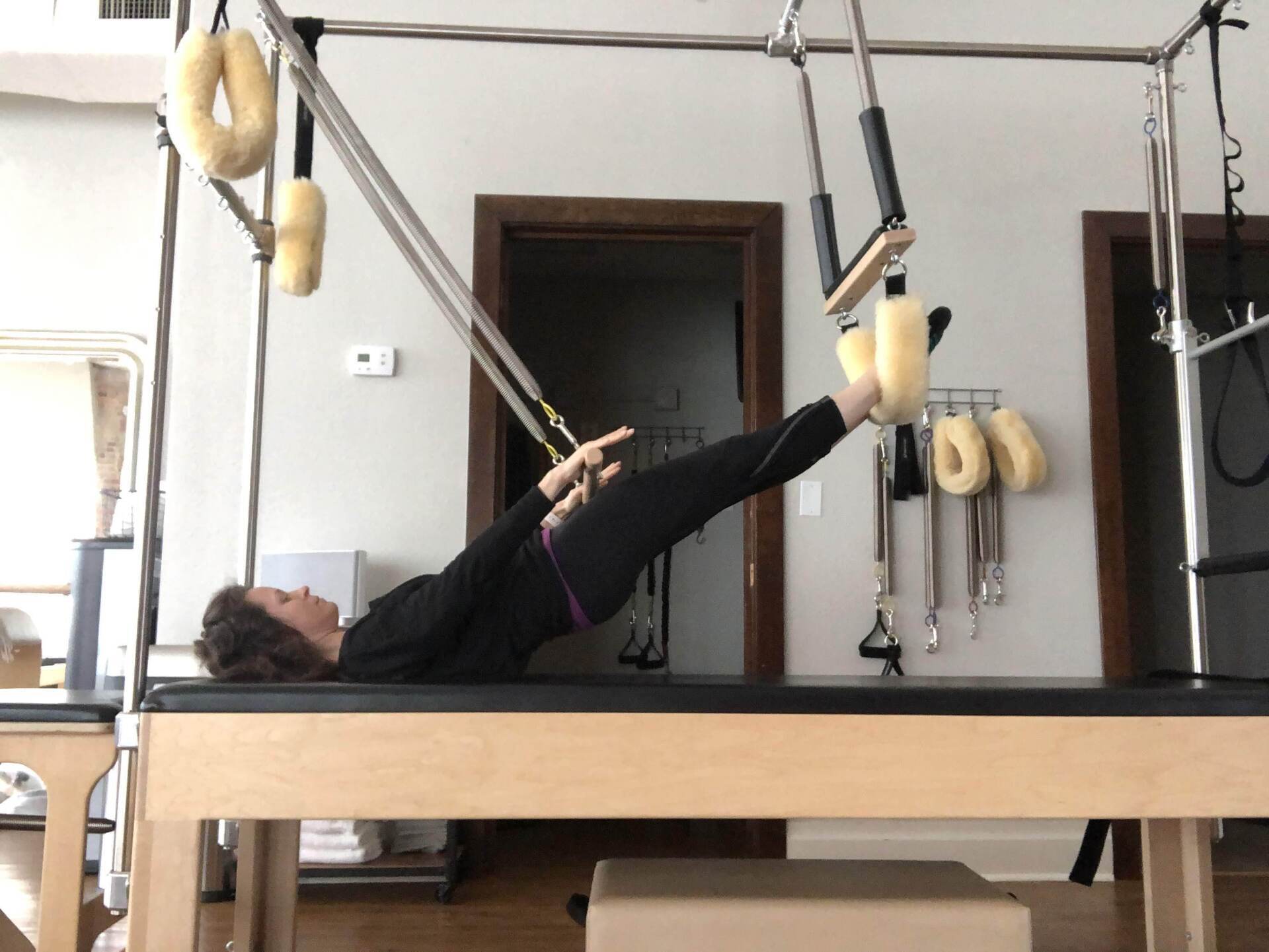 A woman is doing a pilates exercise on a pilates machine.