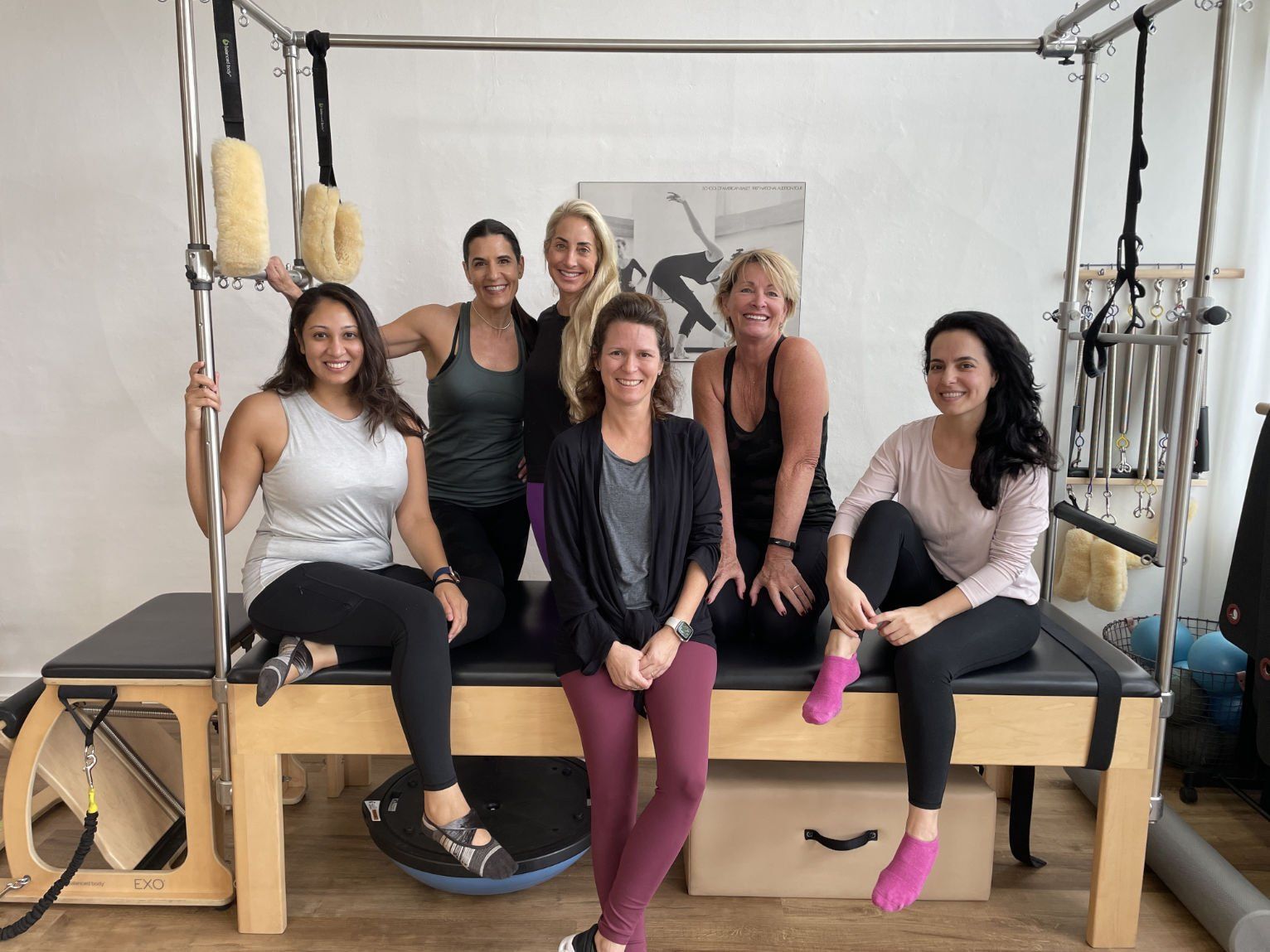 A group of women are sitting on top of a pilates machine.