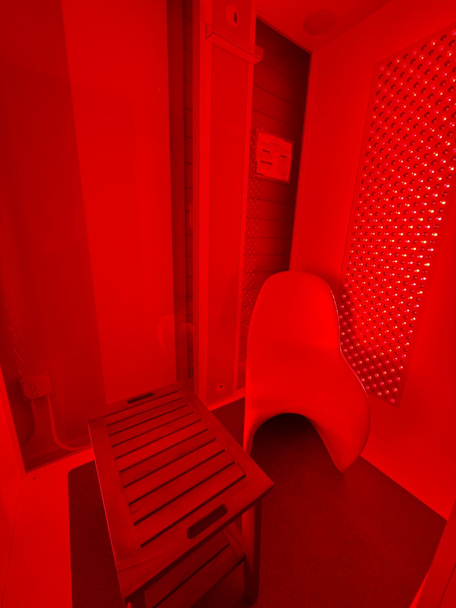 Red light therapy room with a chair and step stool.