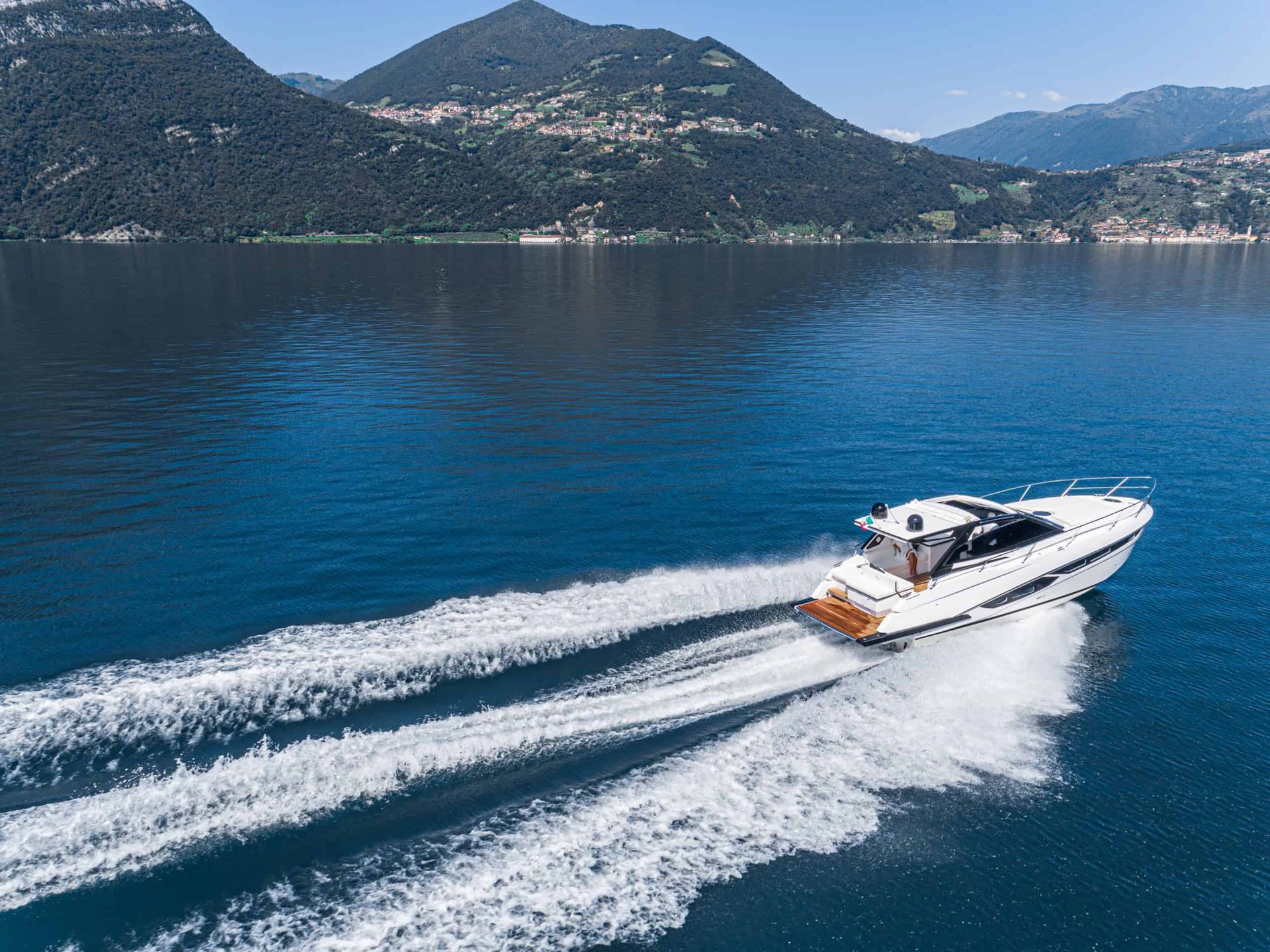 Aerial view of speed boat. A boat is floating on top of a lake with mountains in the background.