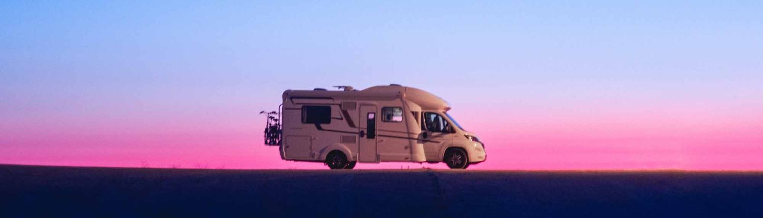 Adventure campervan motor home at sunset A rv is driving down a road at sunset.