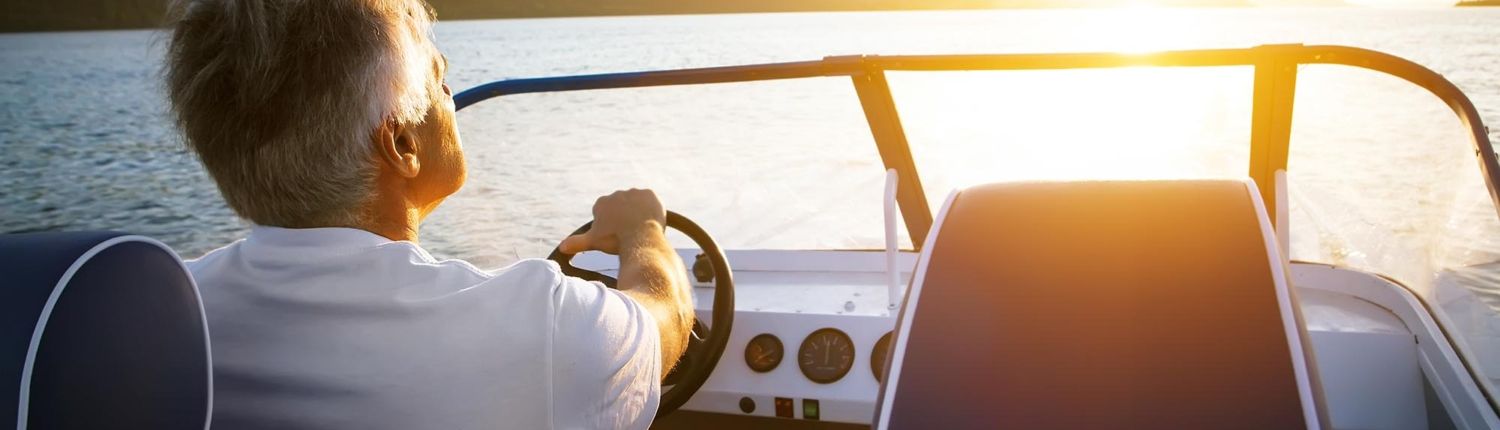 Back view of a man driving a boat on a lake Back view of a man driving a boat on a lake