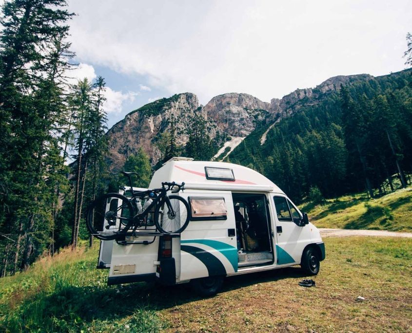 Cute vintage camper van or camping RV parked in wild camping spot in mountain forest Cute vintage camper van or camping RV parked in wild camping spot in mountain forest