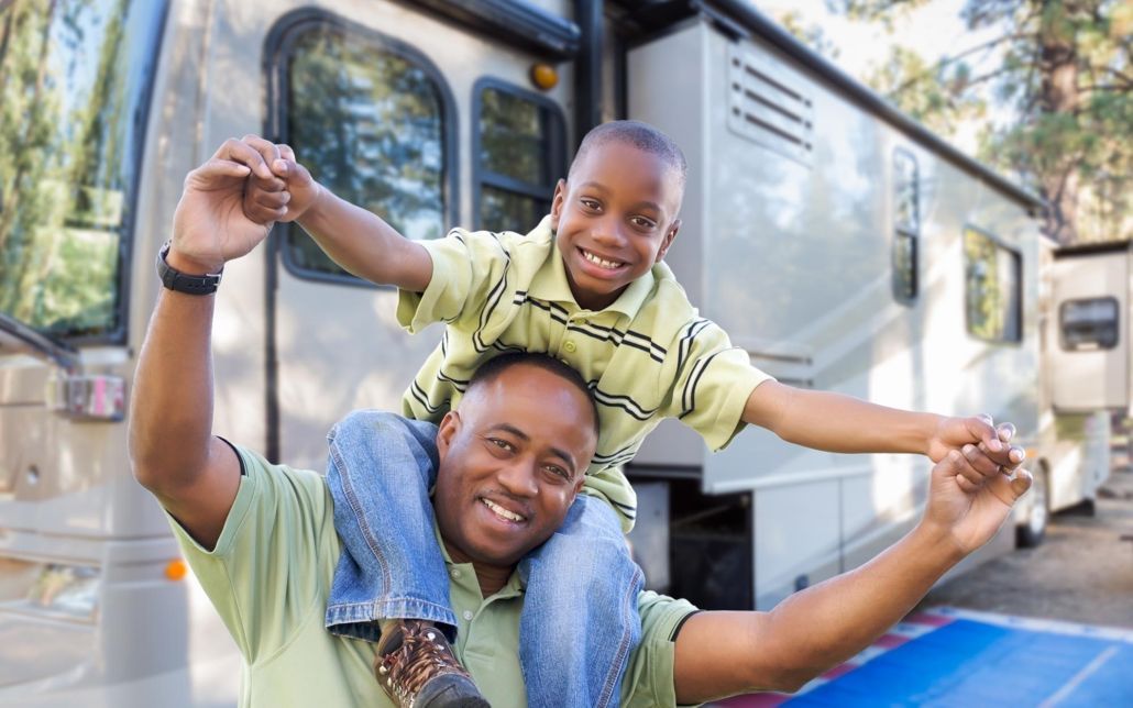 Child on dads shoulders infront of RV
