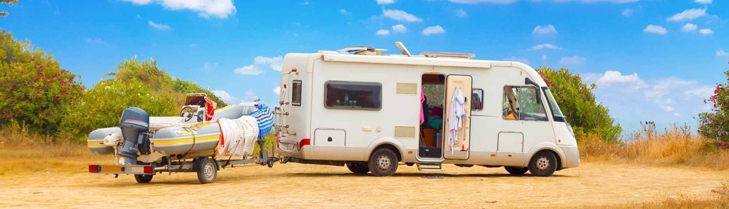 Rv with an inflatable boat in a dessert A rv is towing a boat on a trailer.
