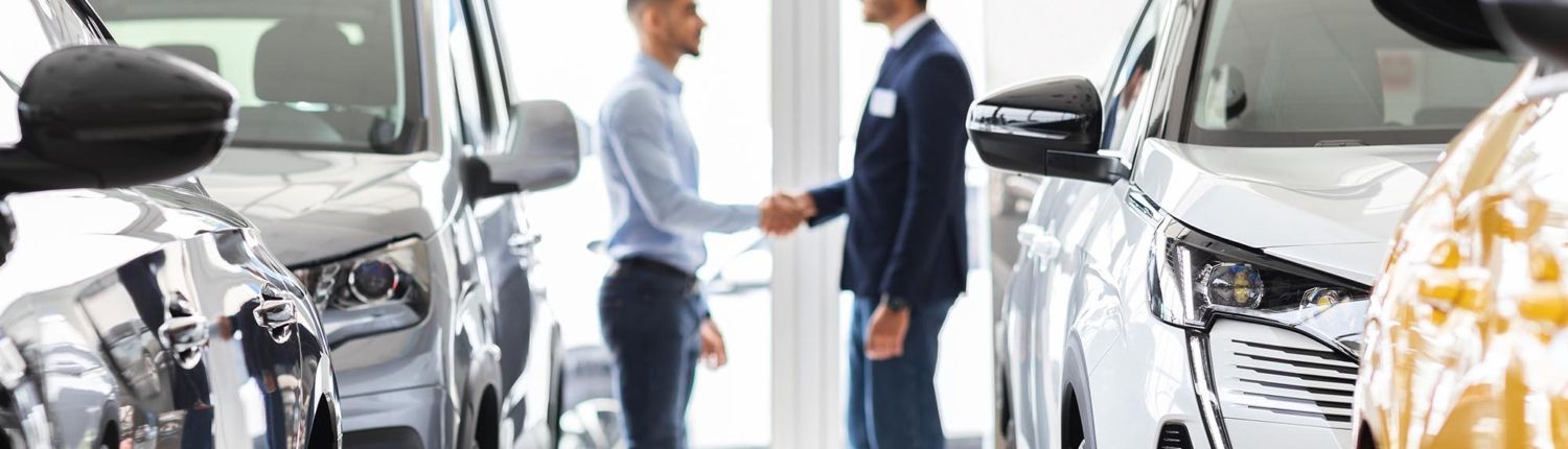 image of two business people shaking hands inside of a car dealership. image of two business people shaking hands inside of a car dealership.
